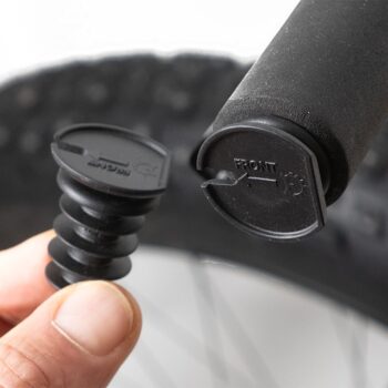 A bar end plug attachment system keeps the pogies from sagging